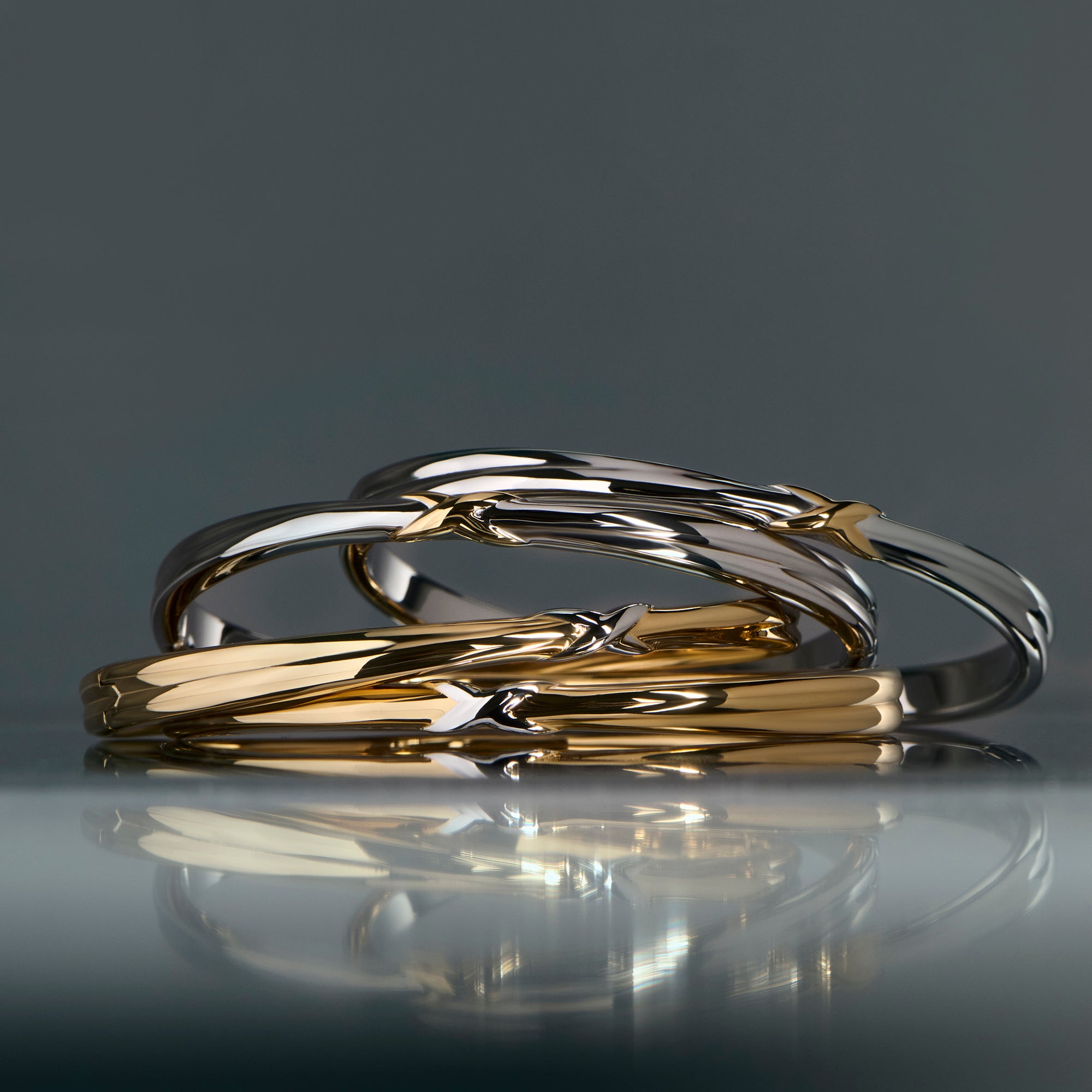 Two-tone stainless steel bangle with sculptural twist design, modern gold and silver minimalist jewelry, hypoallergenic non-tarnish durable rings, elegant everyday stackable jewelry.