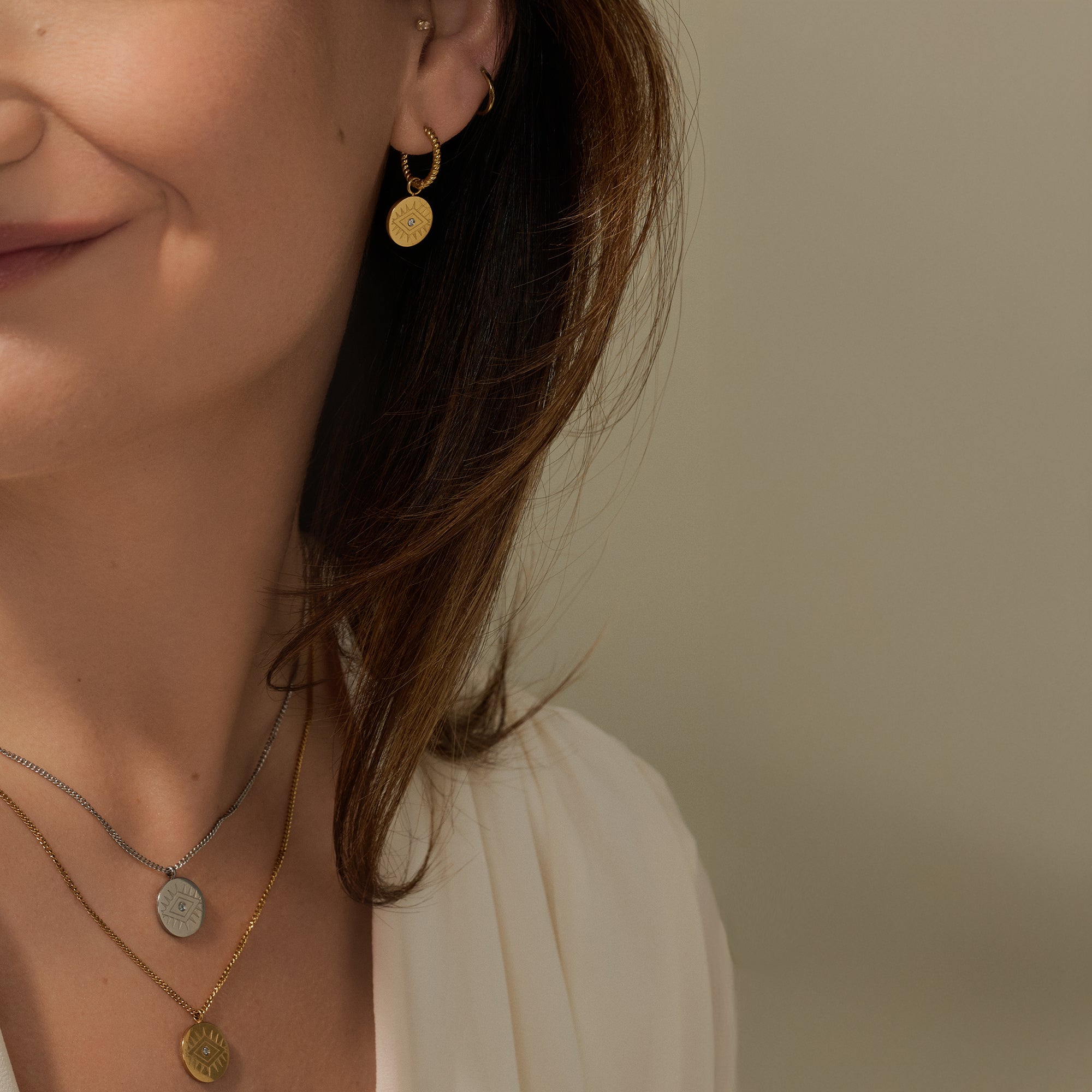 Layered evil eye gold and silver coin pendant necklaces with cubic zirconia, paired with evil eye huggie earrings – hypoallergenic, non-tarnish jewelry by Mia Bijoux Canada