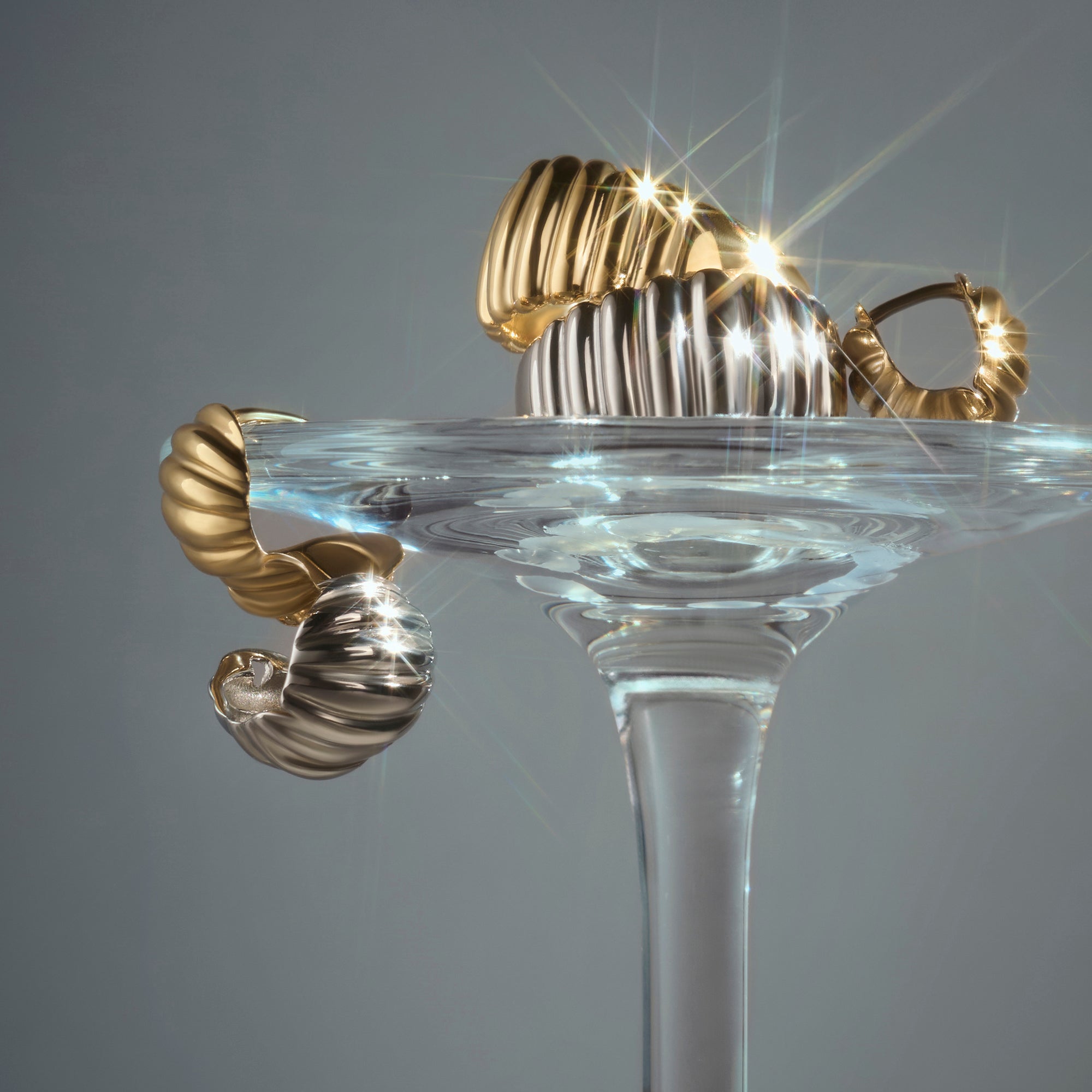 Gold and silver stainless steel ribbed hoop earrings with sculptural shell design, bold modern jewelry, hypoallergenic non-tarnish durable earrings, elegant contemporary statement jewelry.