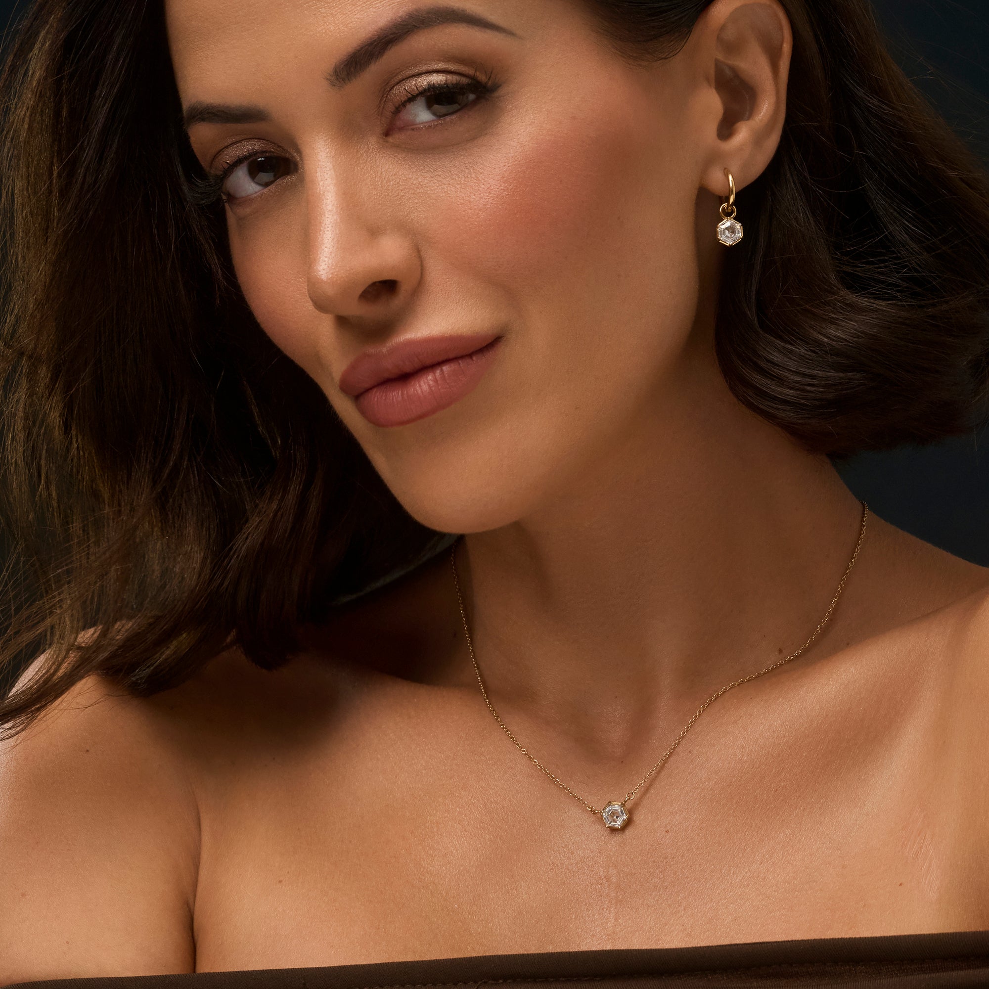 Gold stainless steel necklace with hexagon cubic zirconia pendant styled with matching drop earrings, elegant geometric jewelry set with brilliant stone and delicate chain.